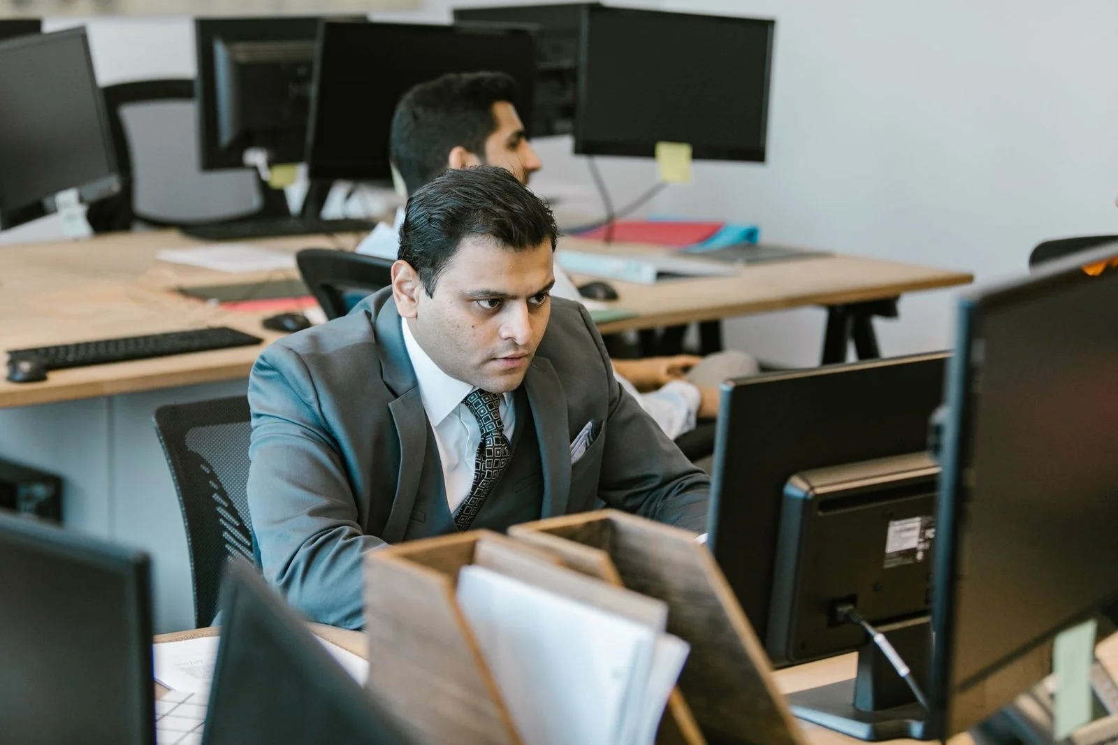 A businessman in a suit focuses on paperwork at a modern office desk.