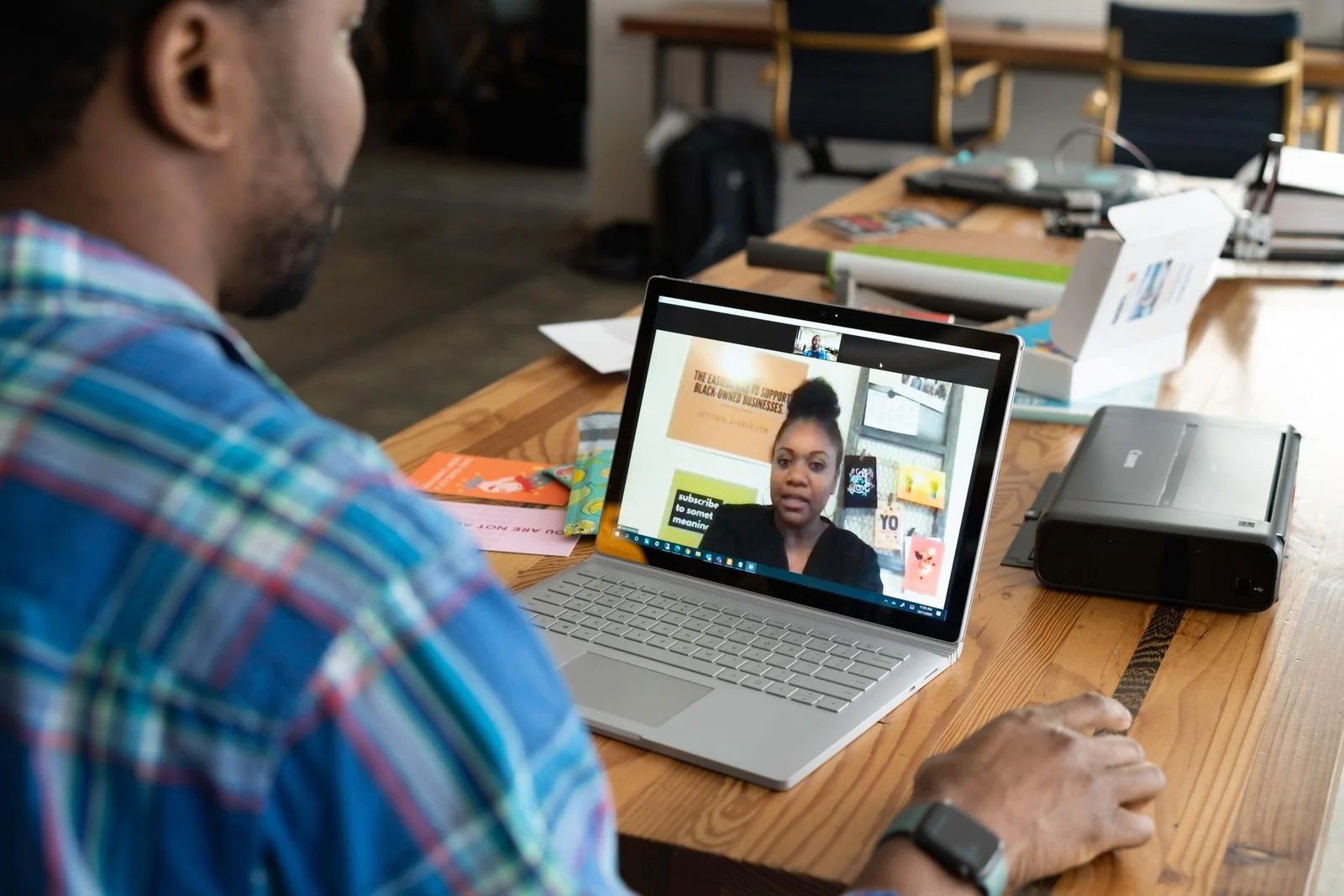 A businessman joins a virtual meeting on his laptop at a desk in an office.