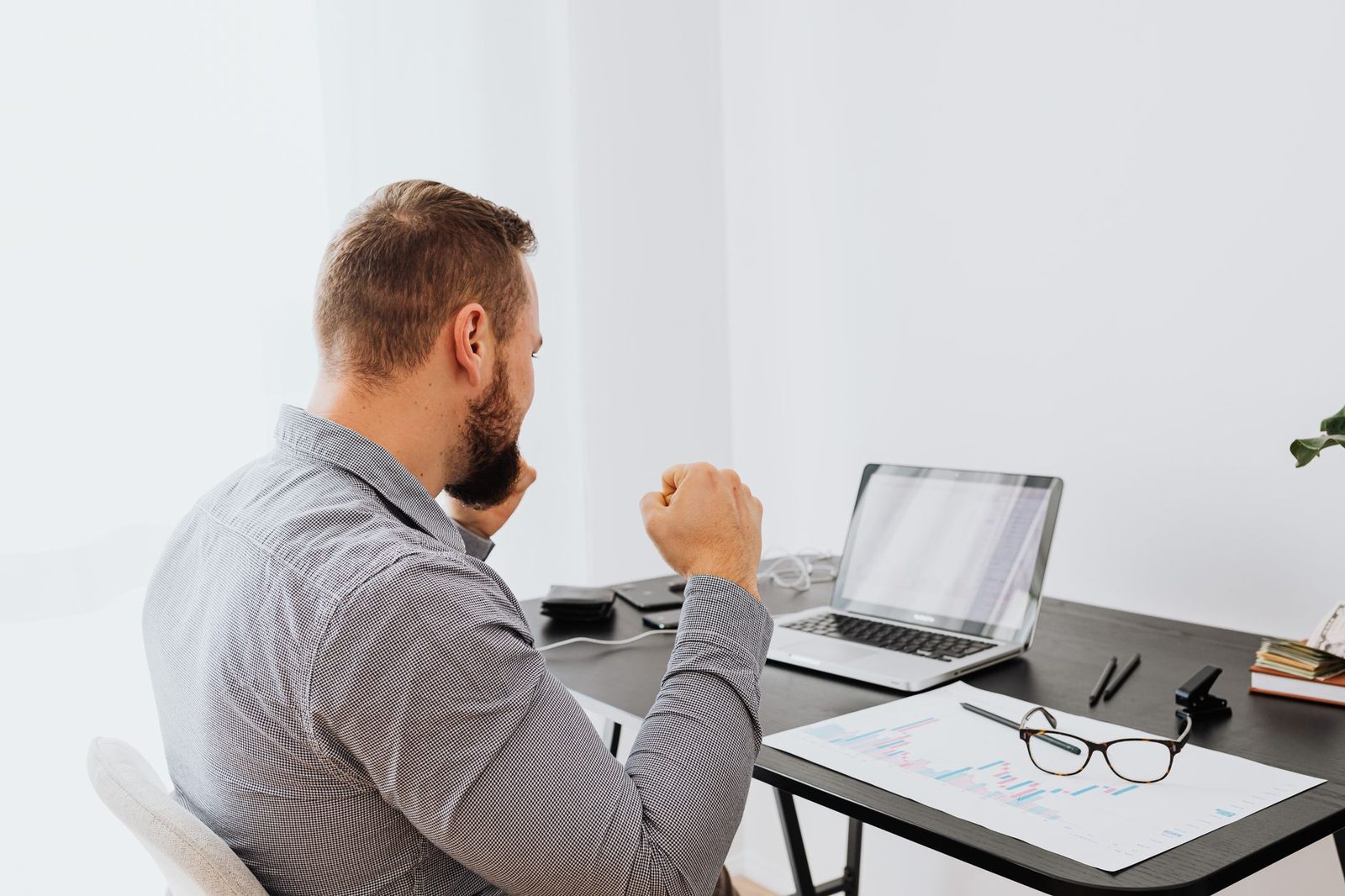 Un hombre de negocios estudia gráficos en una laptop sobre un escritorio moderno.