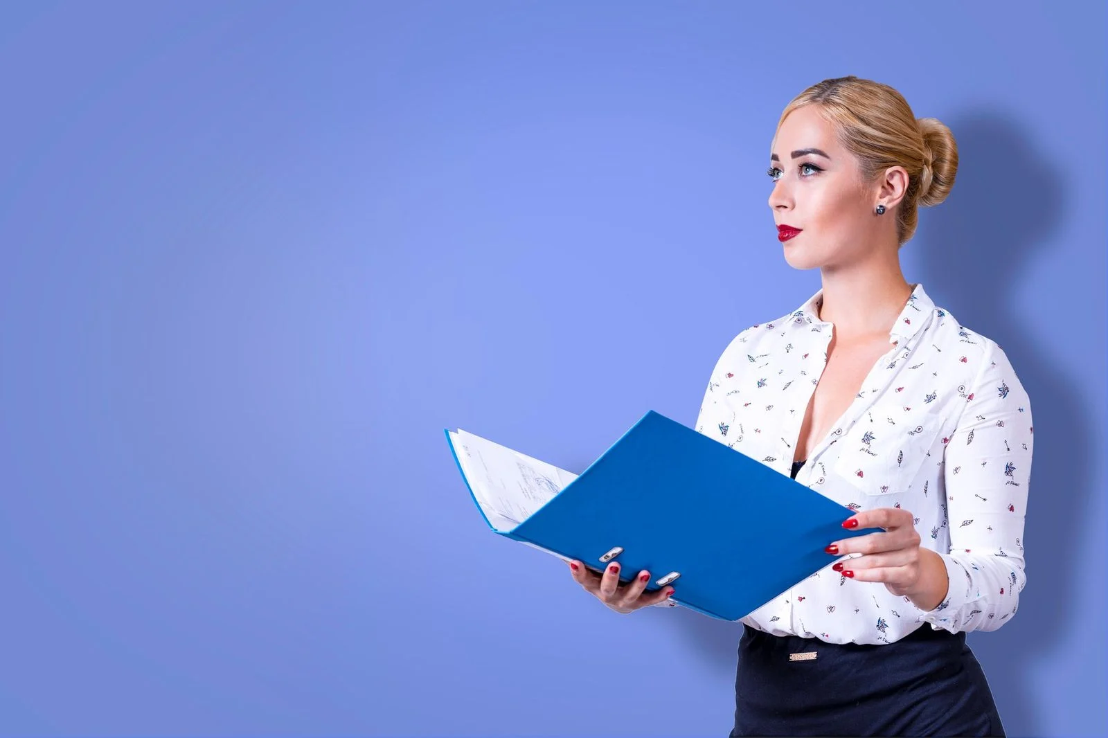 Mujer de negocios con traje sosteniendo una carpeta azul frente a un fondo azul.