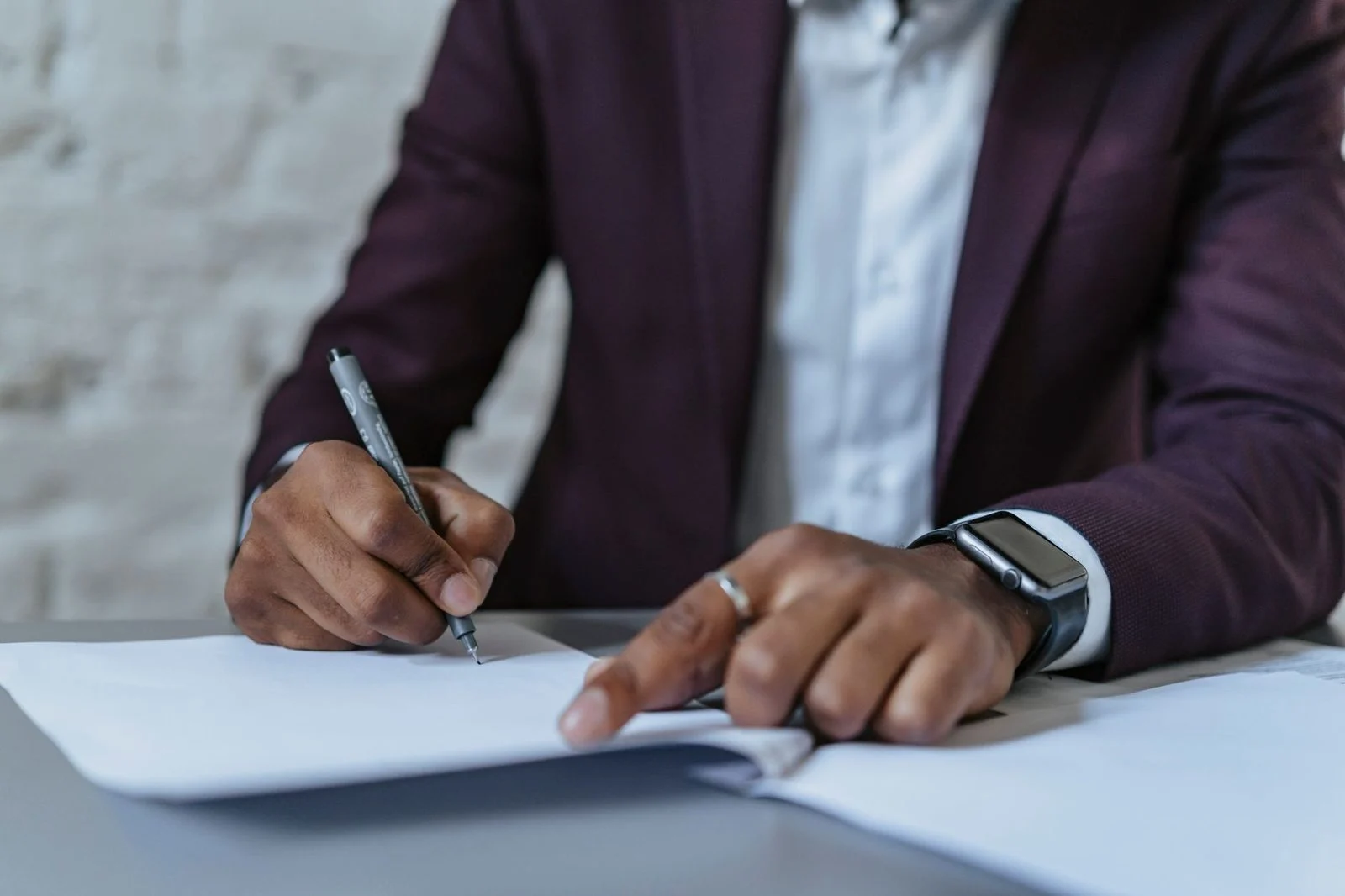 A close-up of a man in a professional office signing documents.