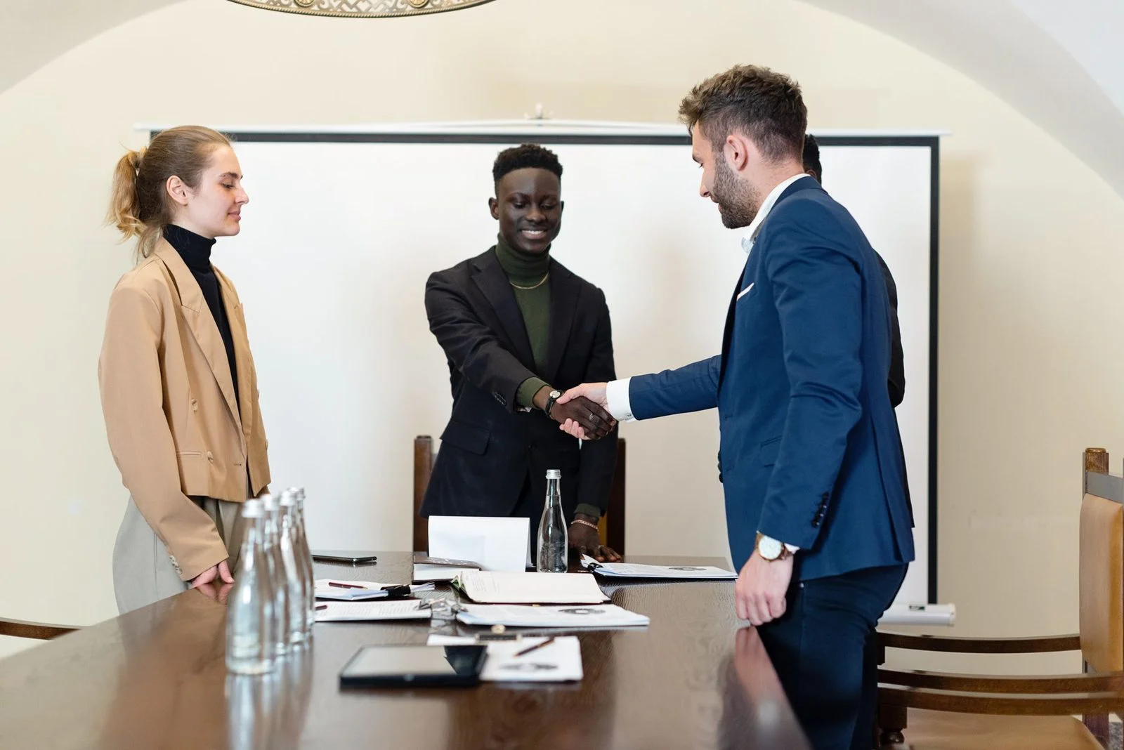 A diverse group of business professionals in a meeting room shaking hands to seal an agreement.