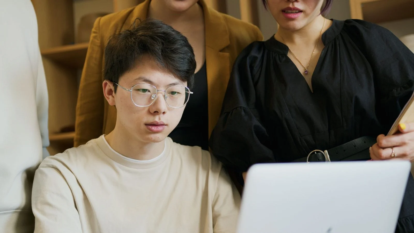 Un equipo diverso se reúne alrededor de una laptop durante una reunión de trabajo en una oficina.