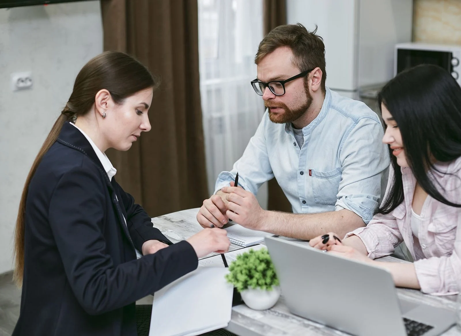 A couple reviews financial documents with an advisor at a desk.
