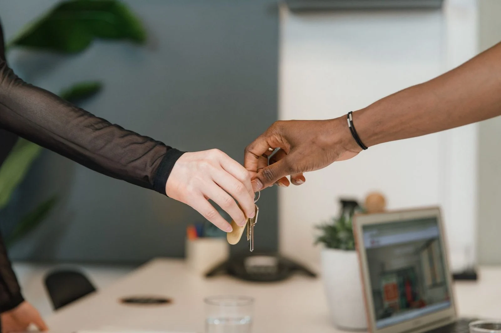 A key being handed across a desk in a professional office setting.