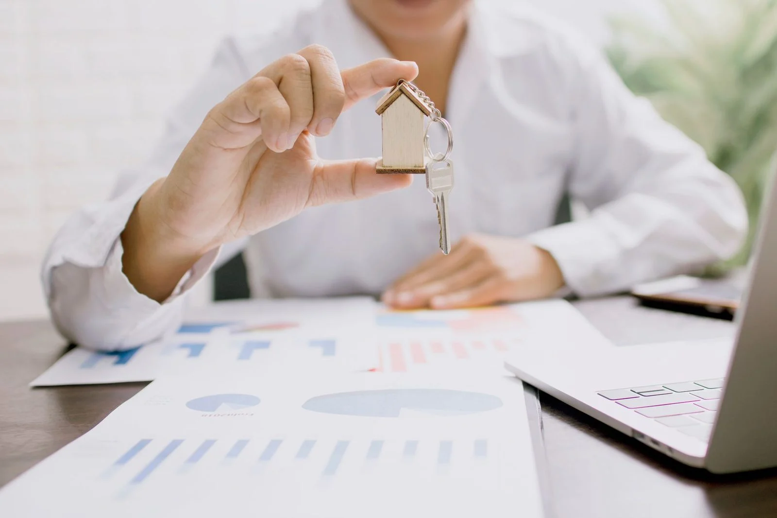 A real estate professional holds a house model and keys during a property investment presentation.