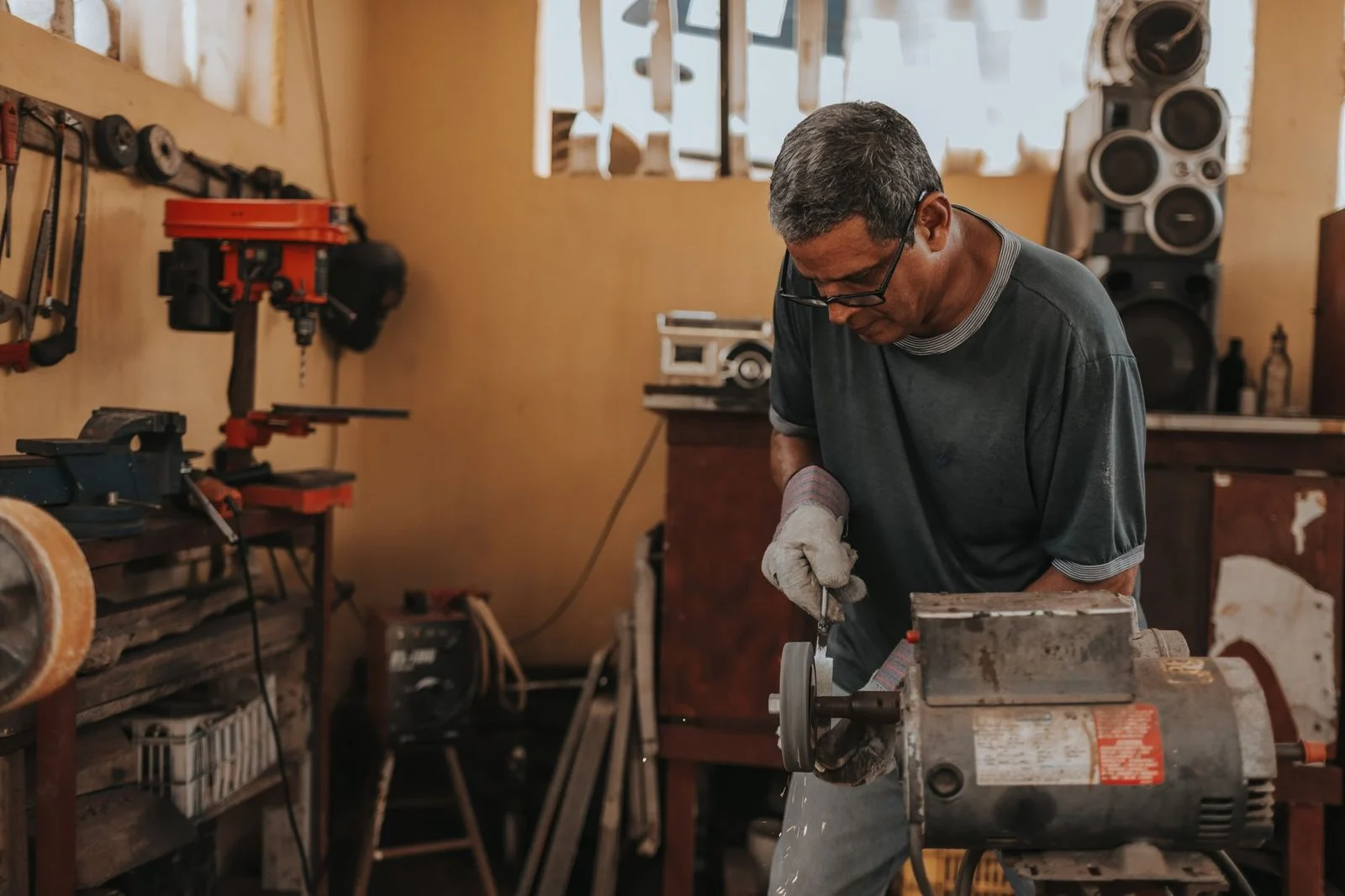 A skilled artisan works on metal with precision tools in a workshop.