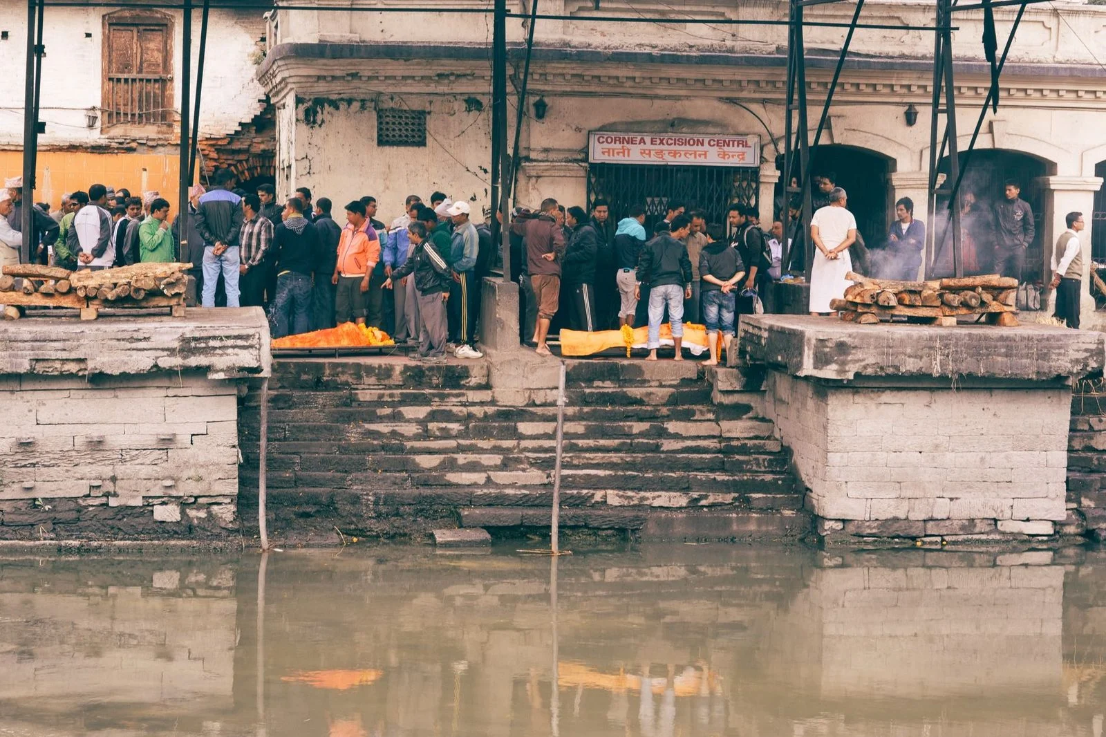 A traditional funeral ceremony held beside a river in a city setting.
