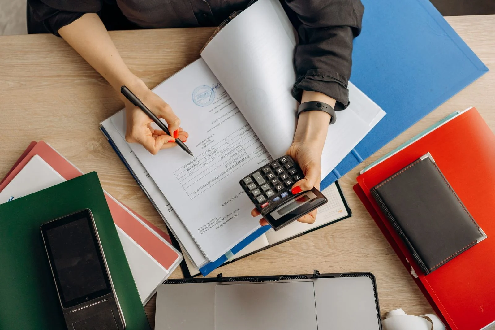 Contador con calculadora revisa documentos financieros en un escritorio, enfocado en planificación fiscal y patrimonial.