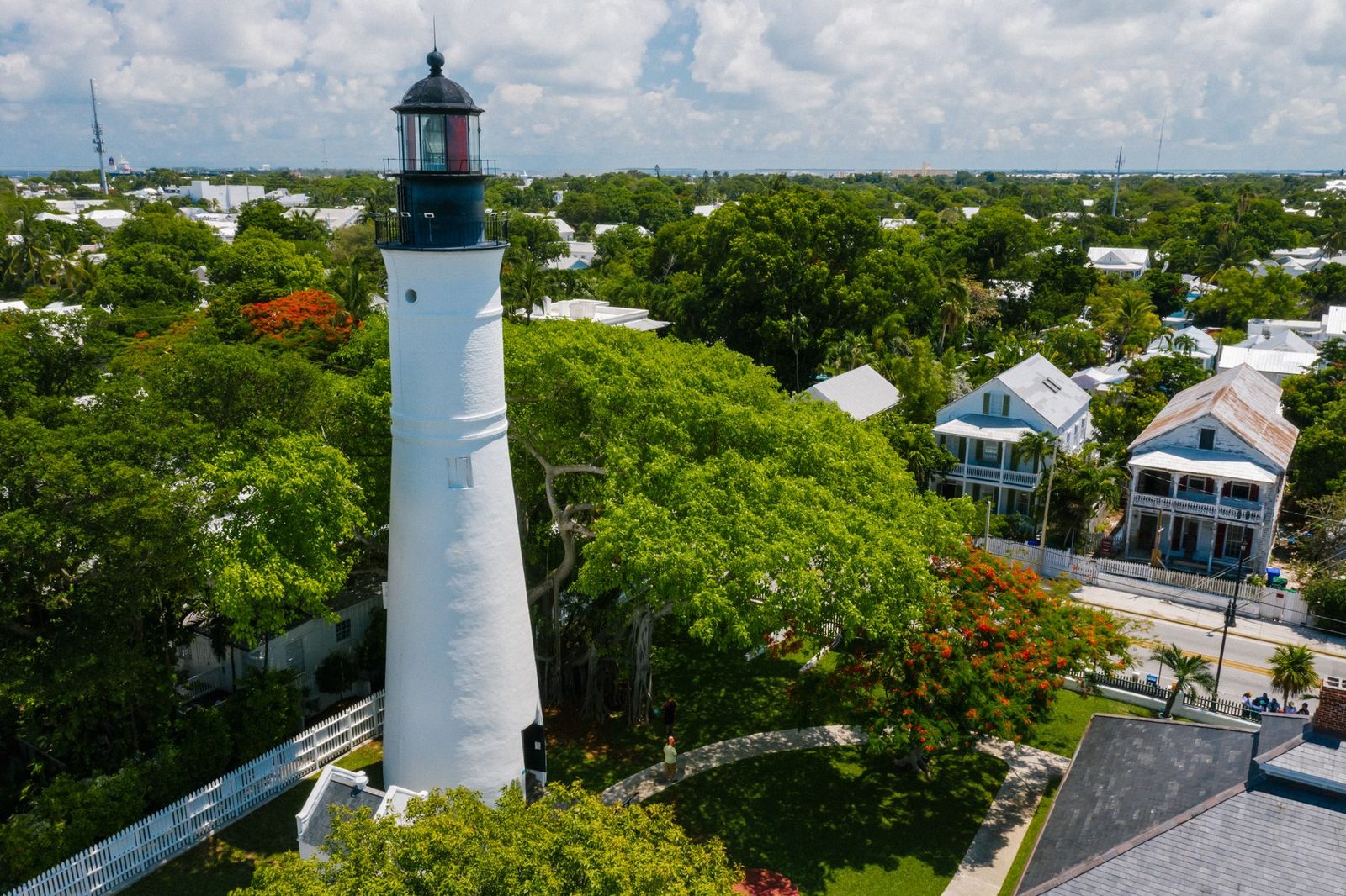 Vista aérea del faro de Key West rodeado de exuberantes árboles verdes y casas históricas.