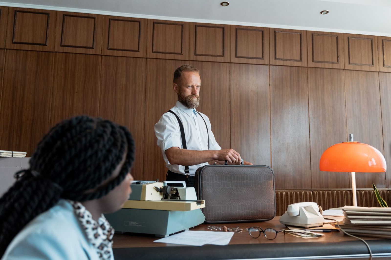Bearded businessman with briefcase working at desk in vintage office.