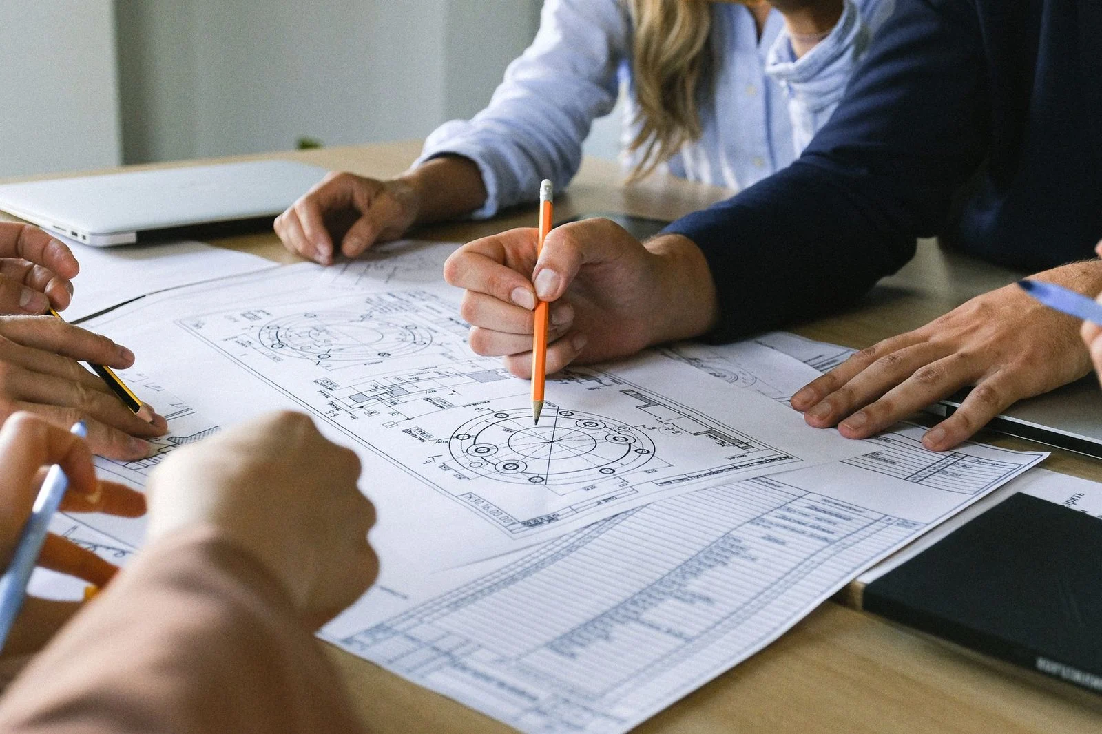 Colleagues gather around a table, reviewing business papers together during a project discussion.