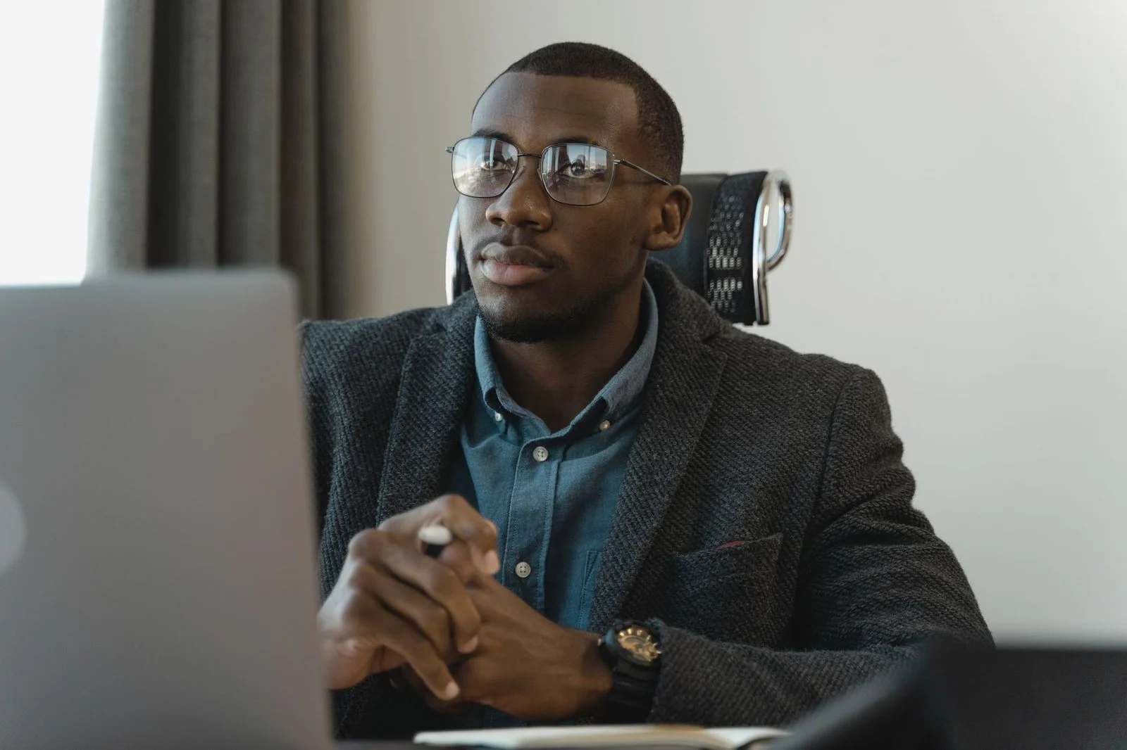 Hombre de negocios con traje trabajando en una laptop en un escritorio moderno.