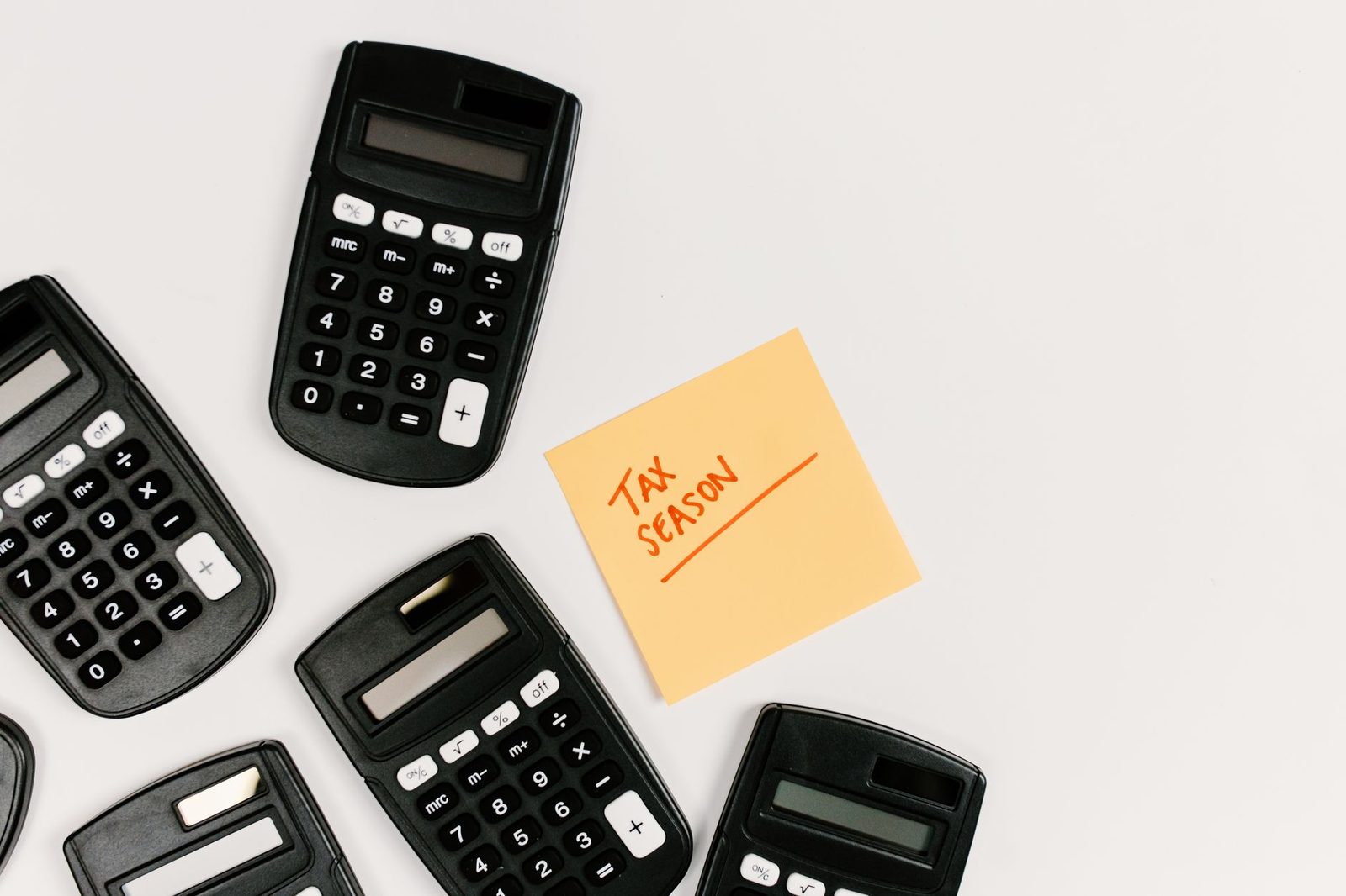 Calculators and tax season sticky note on white background.