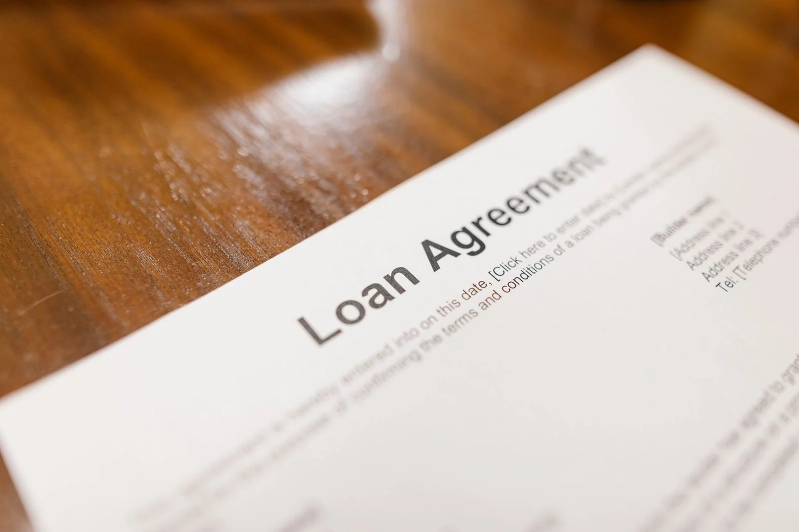 Close-up of a loan agreement document lying on a wooden table, representing the legal and financial concerns of a business loan.