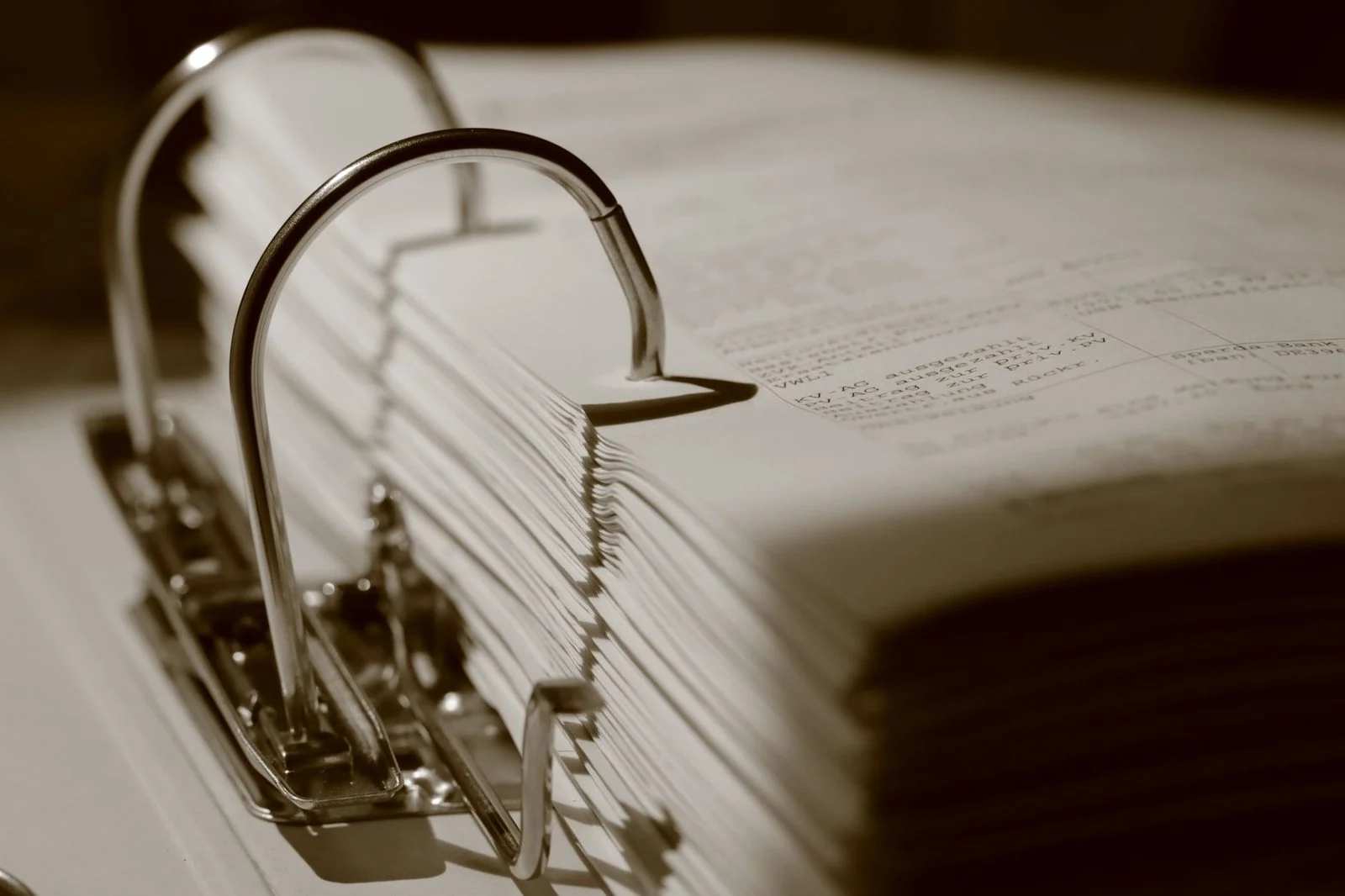 Close-up sepia photo of a binder stuffed with documents, showing the paper and cover texture.