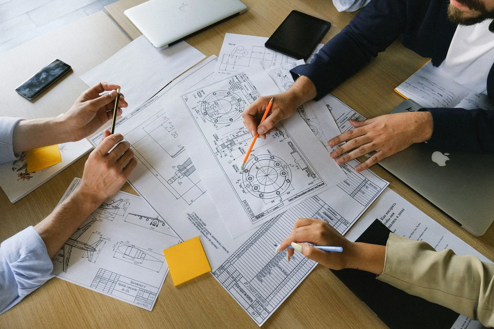Colleagues gather around a table covered in papers and charts, discussing business information.