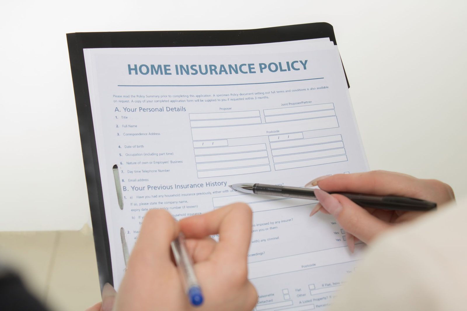 Couple reviewing and signing insurance policy documents together.