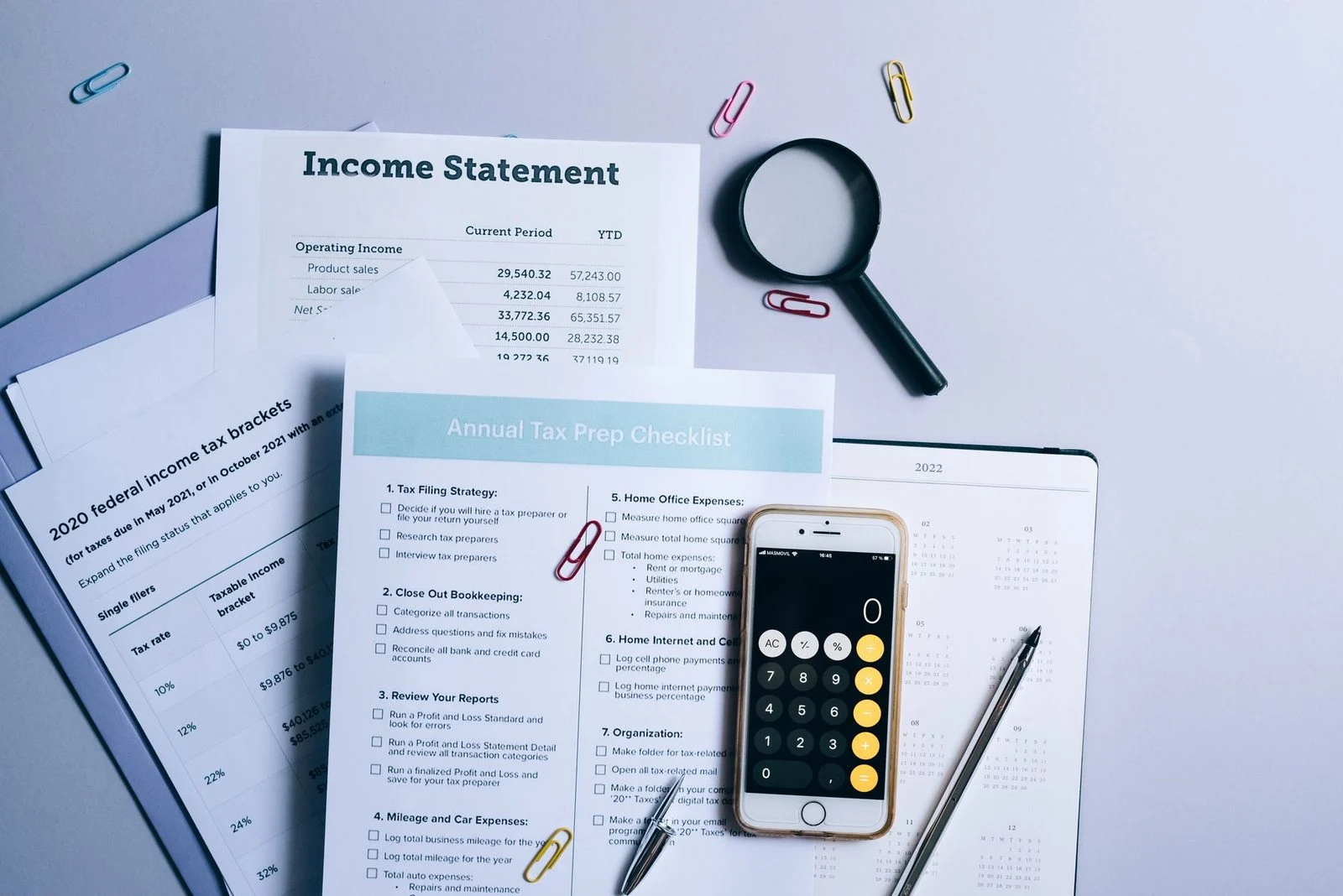 Desk covered with tax forms, a checklist, and a calculator arranged for tax preparation.