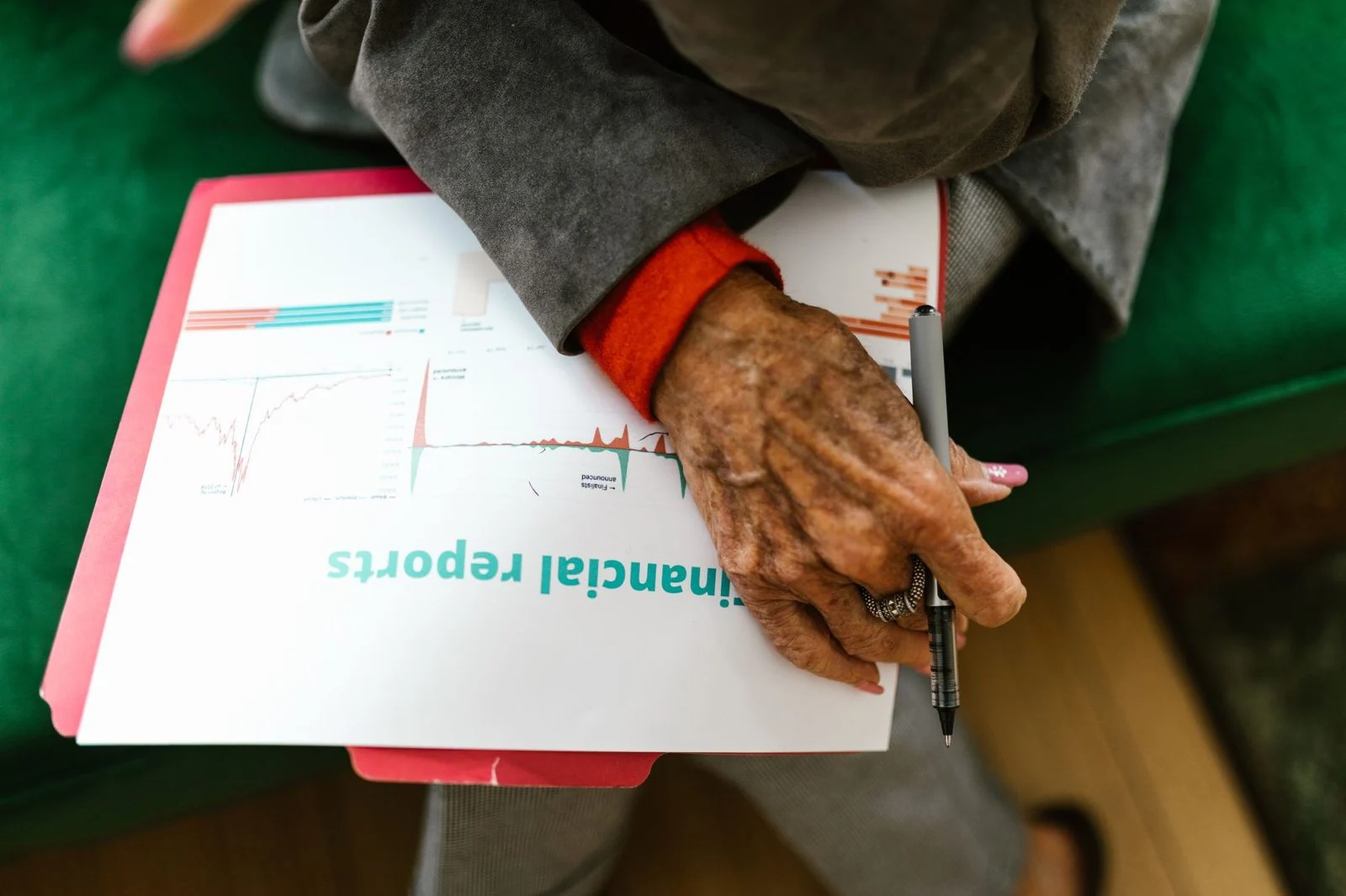 Elderly woman reviewing financial documents with a pen.