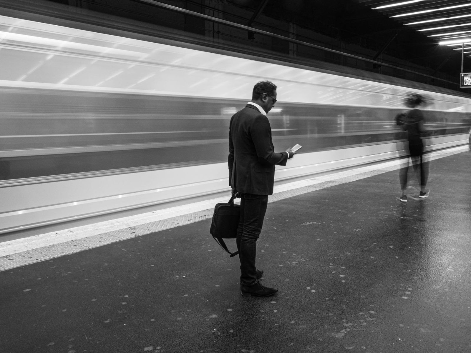 Empresario con teléfono en estación de metro concurrida.