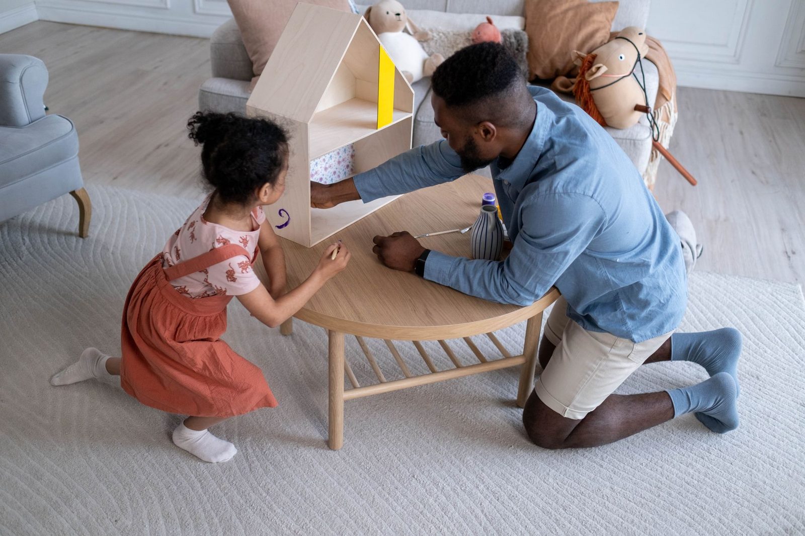 Father and daughter building a dollhouse together at home.