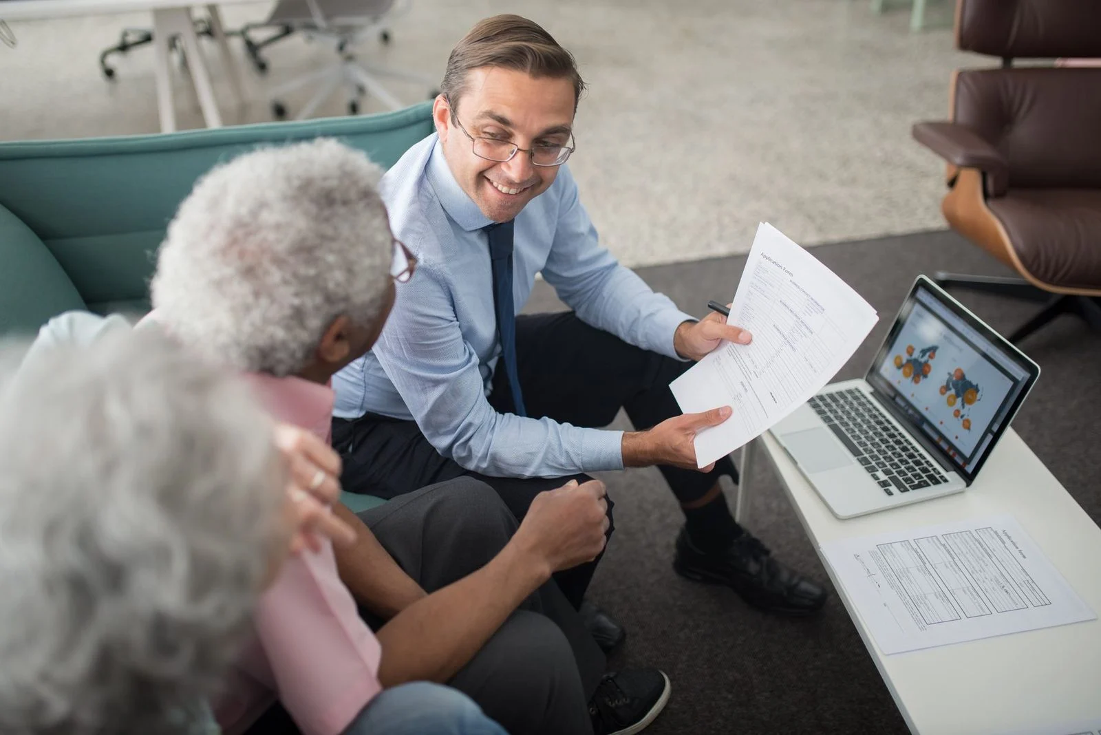 Financial advisor reviewing documents with senior clients in a bright office during a collaborative consultation.
