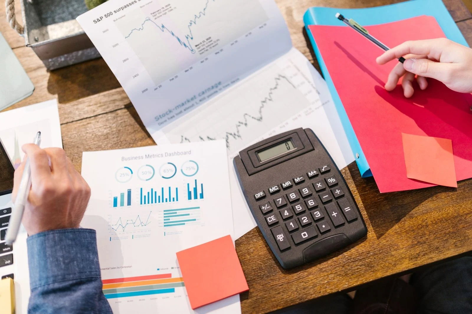 Calculadora y gráficos impresos de planificación financiera dispuestos sobre un escritorio.