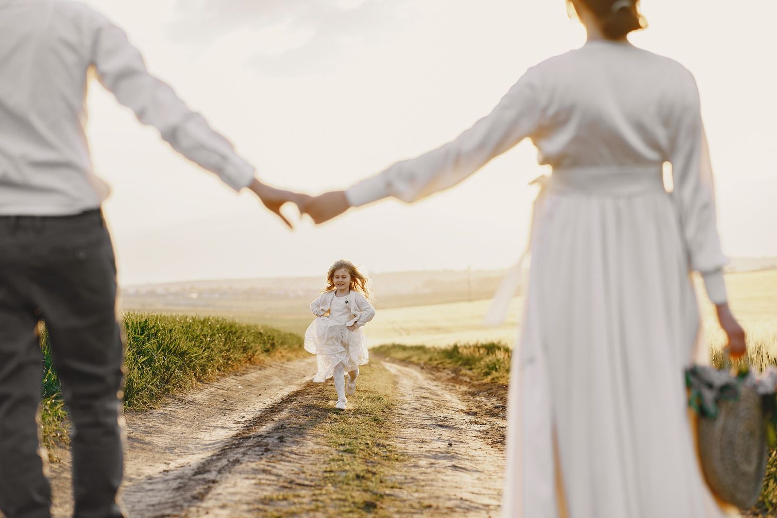 Happy child running toward parents on a sunny rural path.