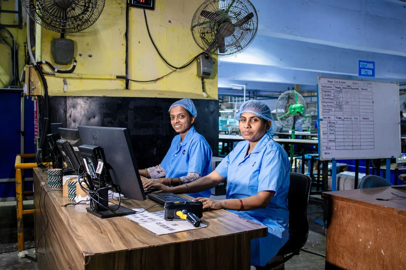 Workers in a textile factory in India use computers on the production floor.