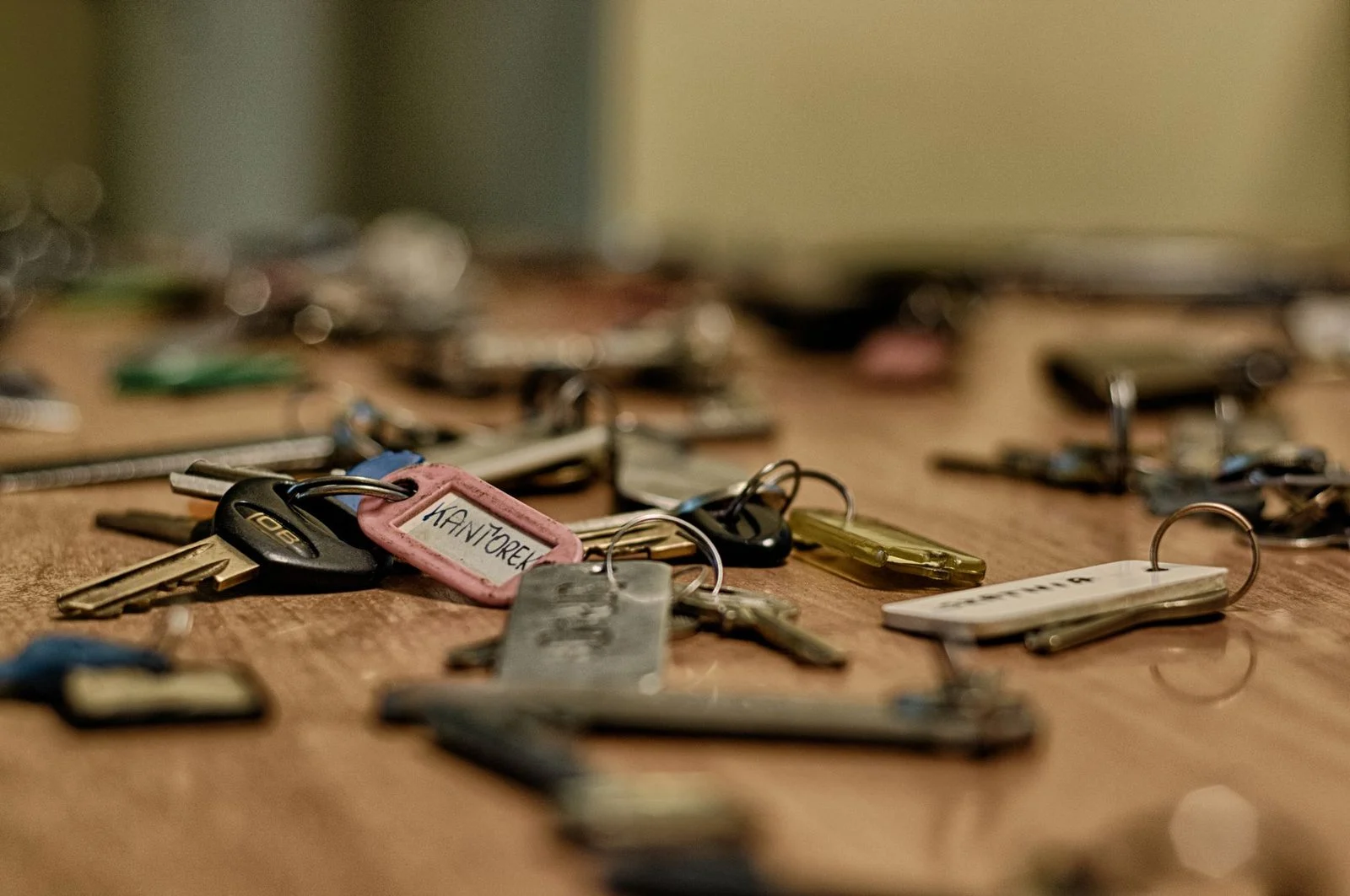 Metallic keys of various shapes scattered across a wooden surface.