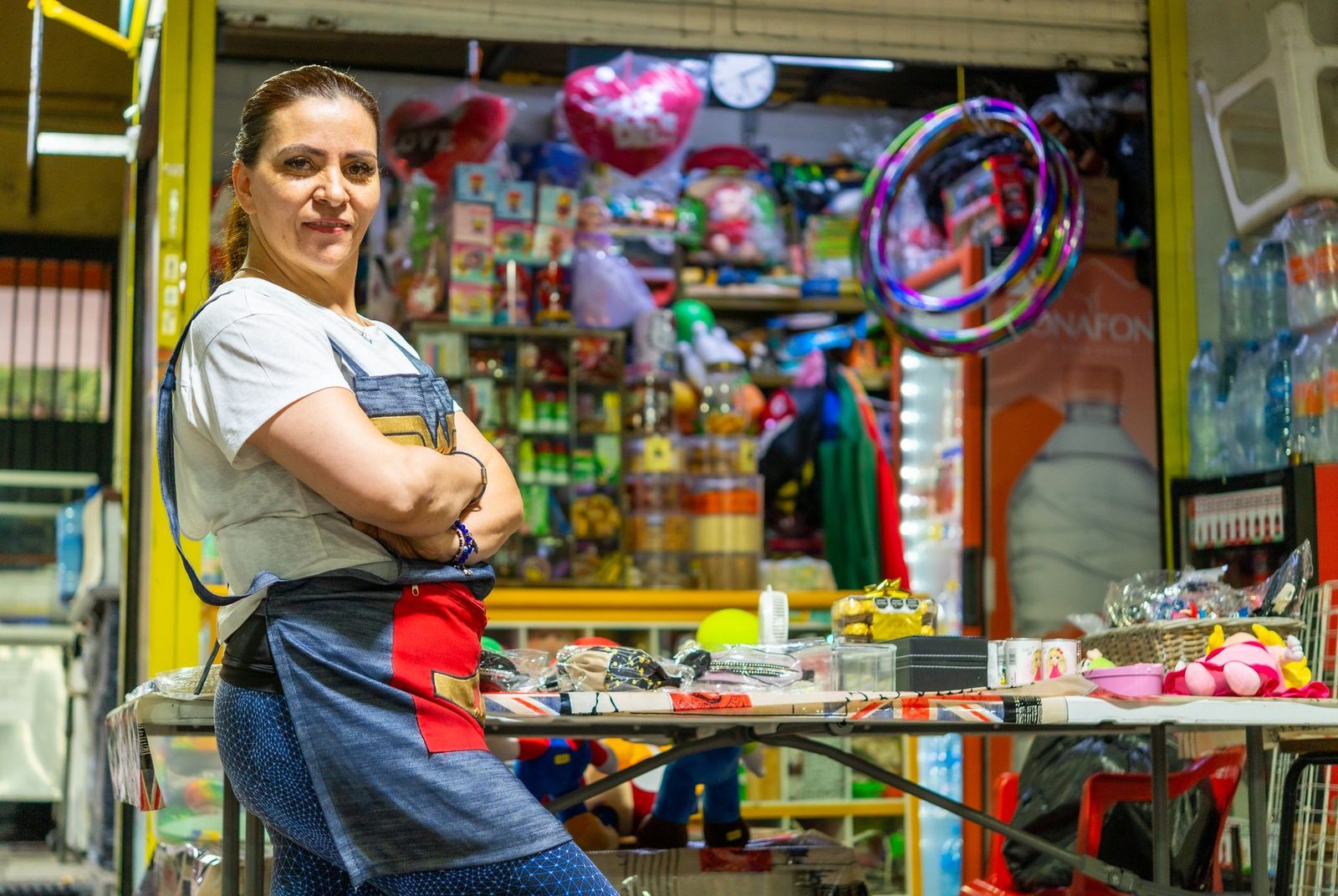 Mujer latinoamericana sonriendo frente a su puesto de mercado colorido en Ciudad de México.
