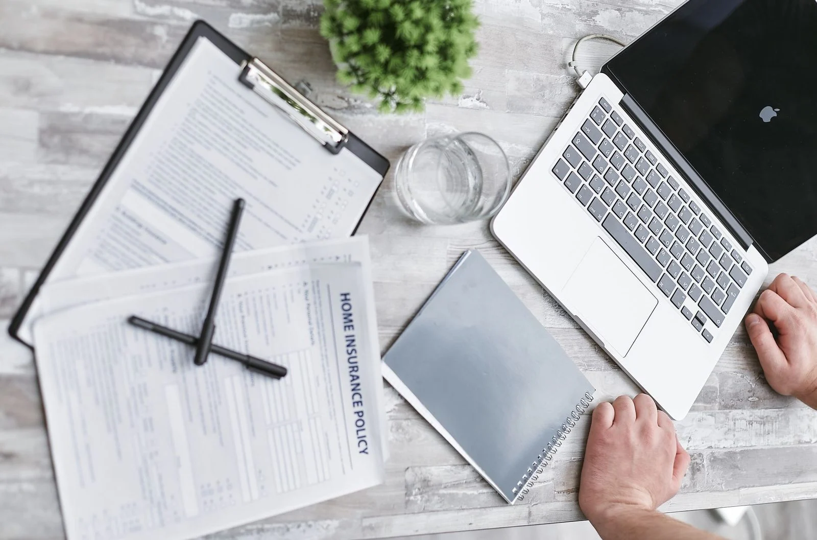 Top-down view of insurance forms, a laptop, and documents arranged on a professional office desk.