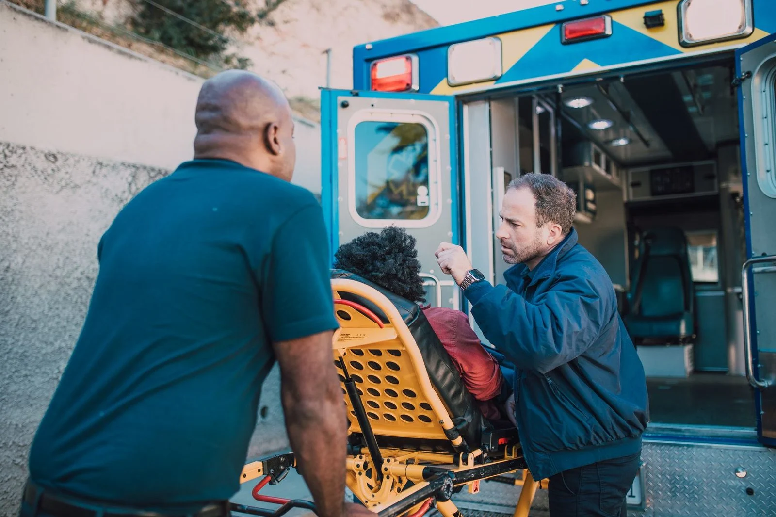 Paramedics help a patient into an ambulance on a city street.