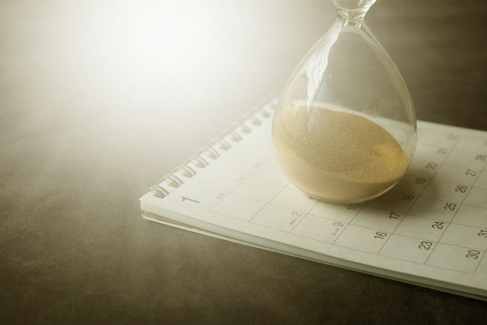 Reloj de arena sobre calendario representando tiempo limitado y urgencia.