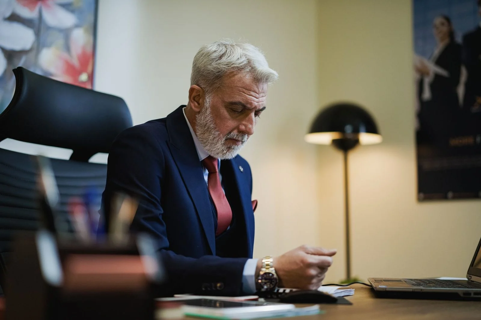 Senior businessman in a suit focuses intently while working at his office desk.