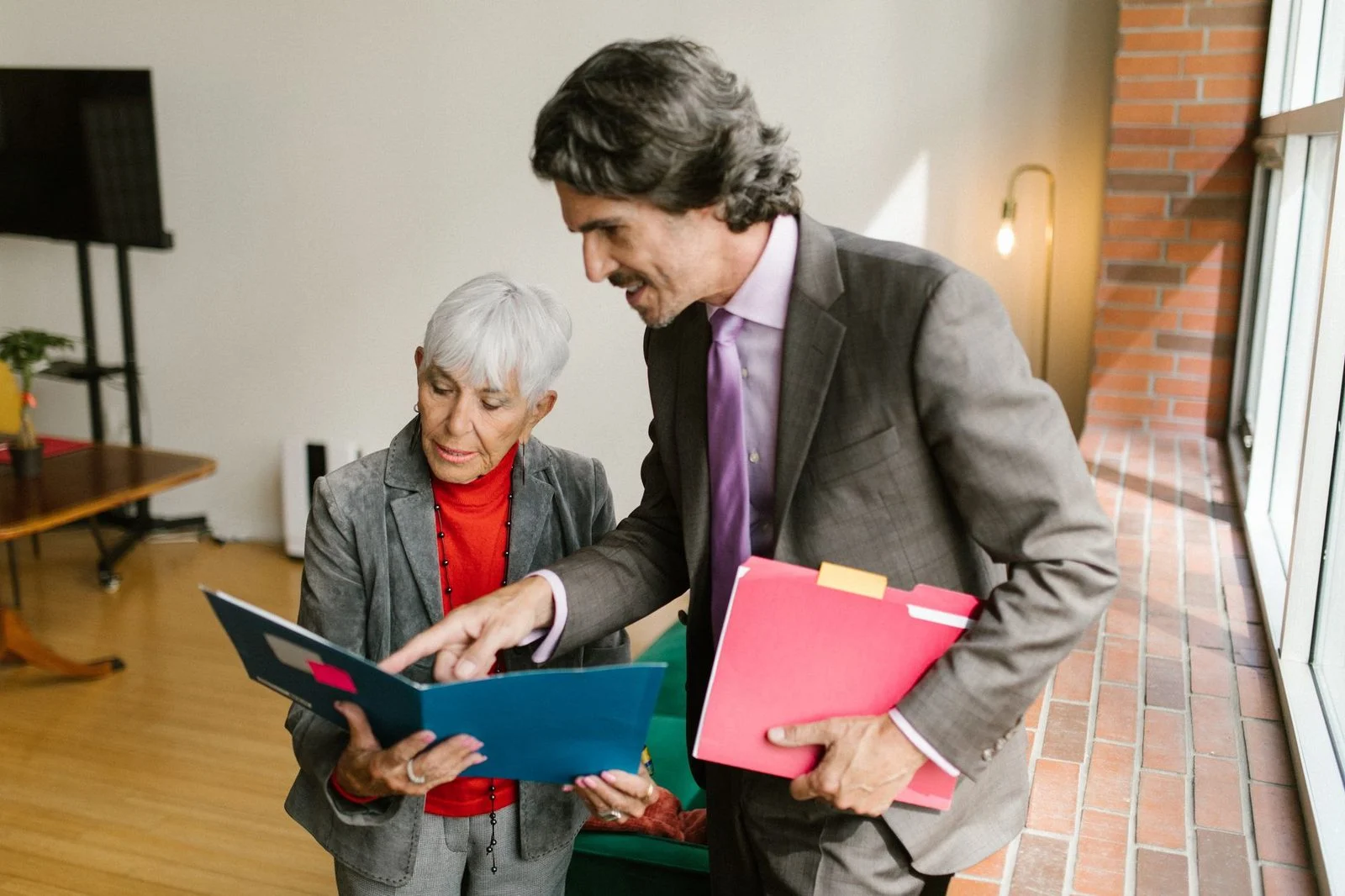 Senior couple reviewing financial documents in bright office setting.