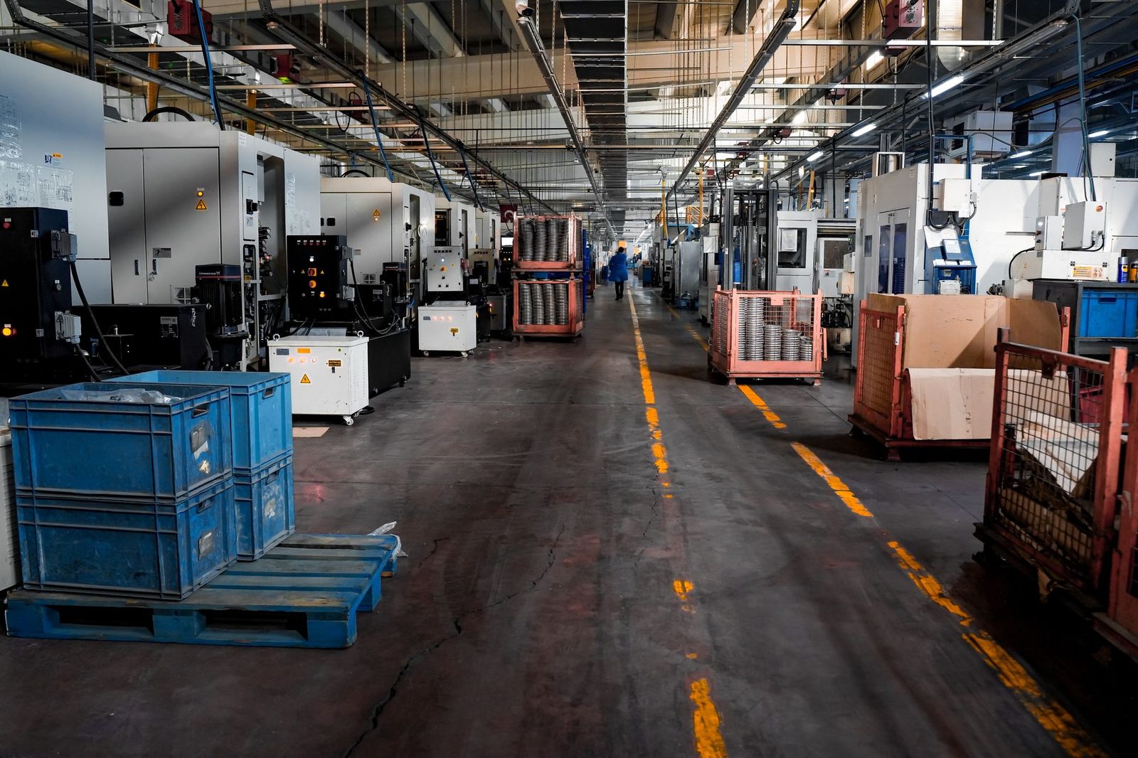 Senior operations manager working at desk in manufacturing facility with colleagues in background.