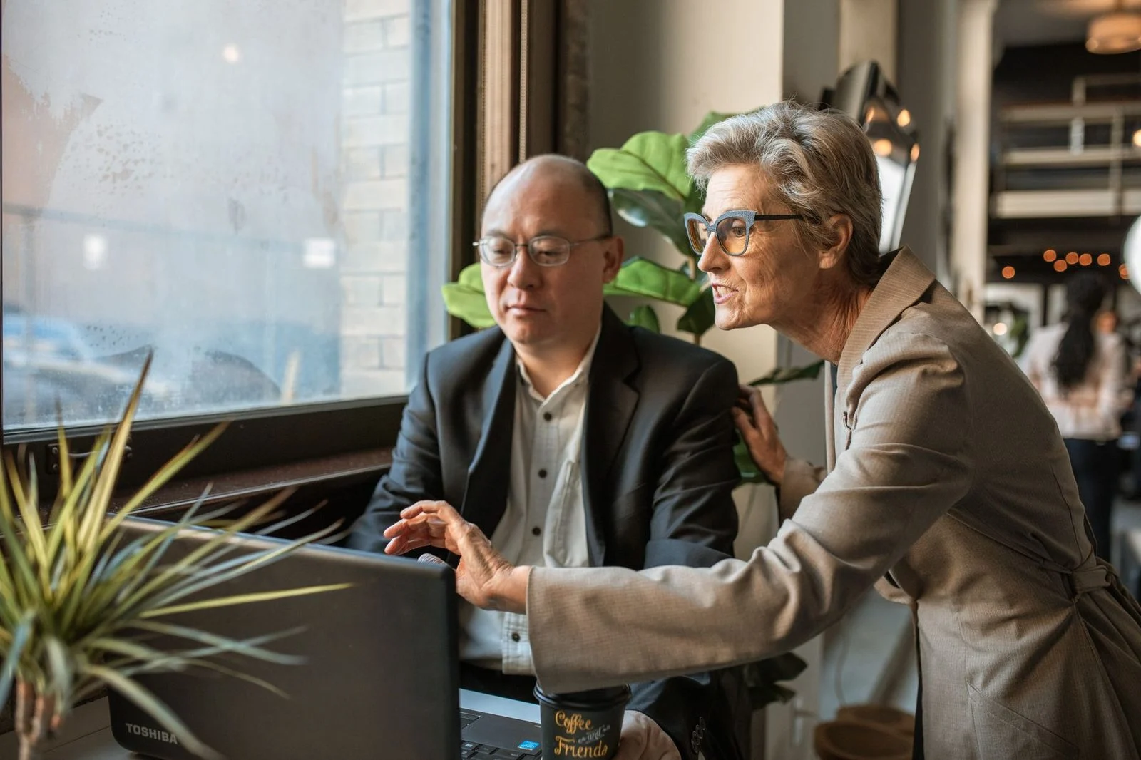 Senior professionals discuss a project together at a modern office workspace.