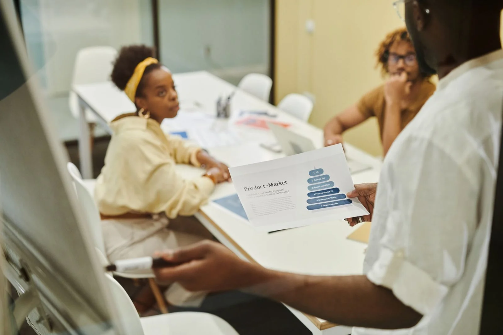 Tres colegas conversan alrededor de una mesa de conferencias durante una reunión de negocios.