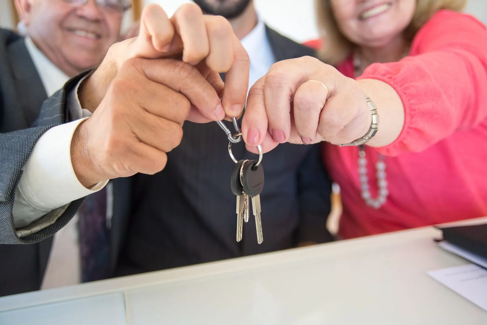 Two business colleagues shake hands over a set of keys, marking a successful deal.