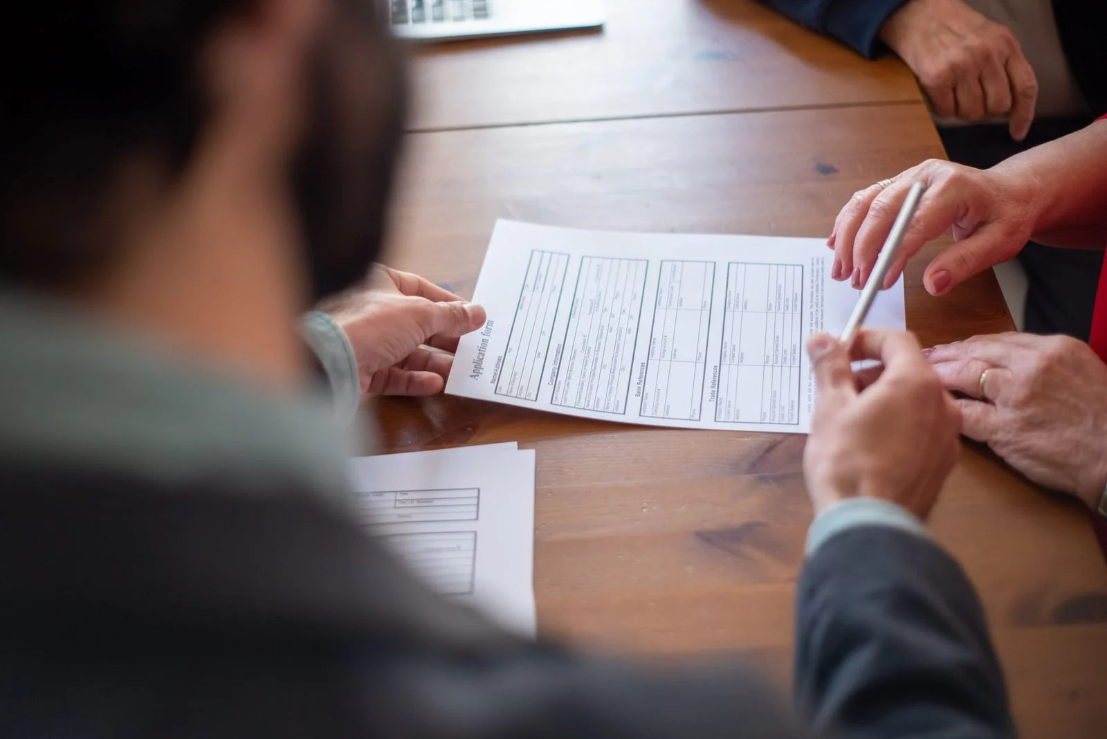 Business professionals review documents together across a conference table during a meeting.
