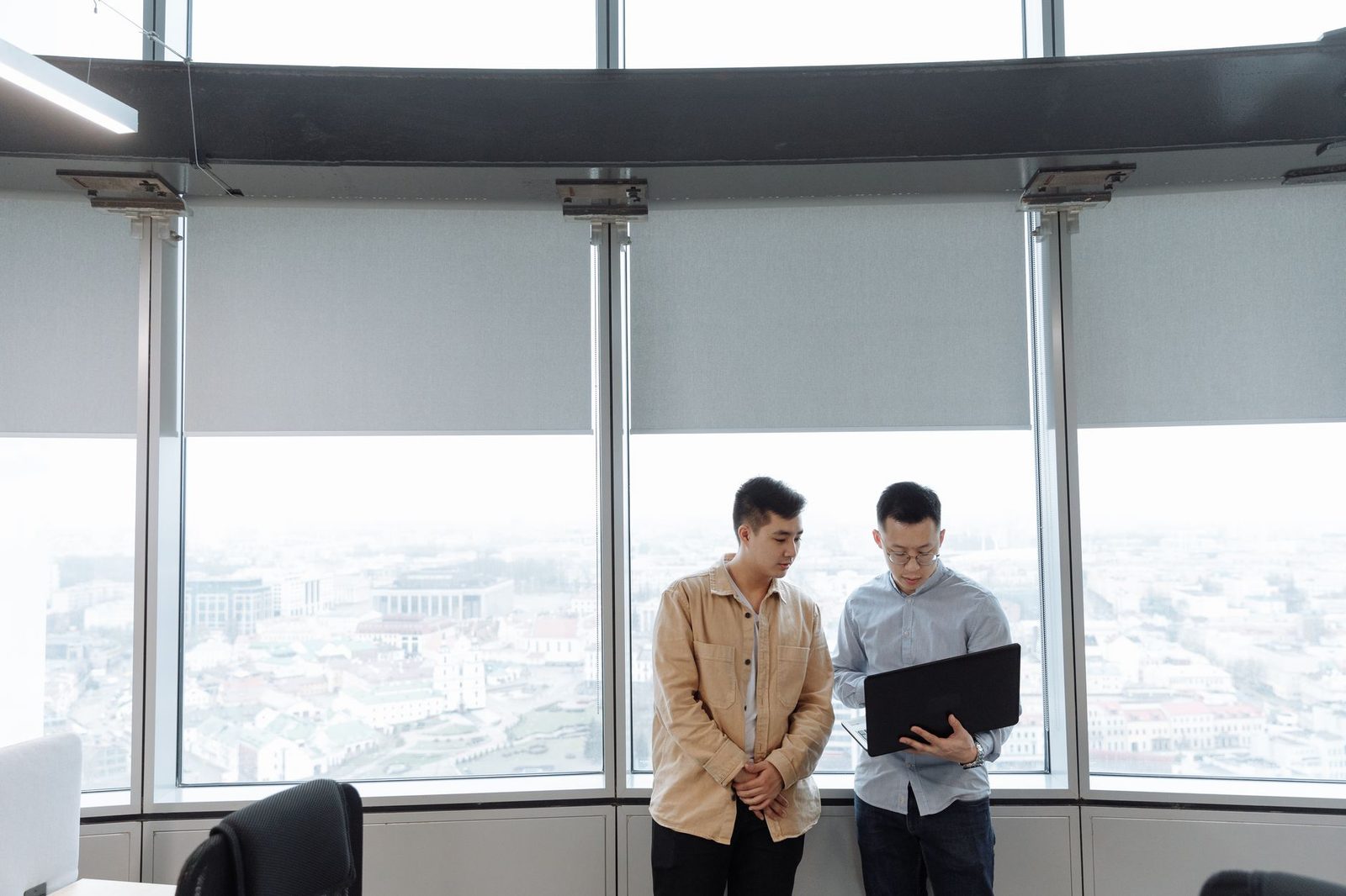 Two business professionals reviewing strategy at a laptop in a modern office.