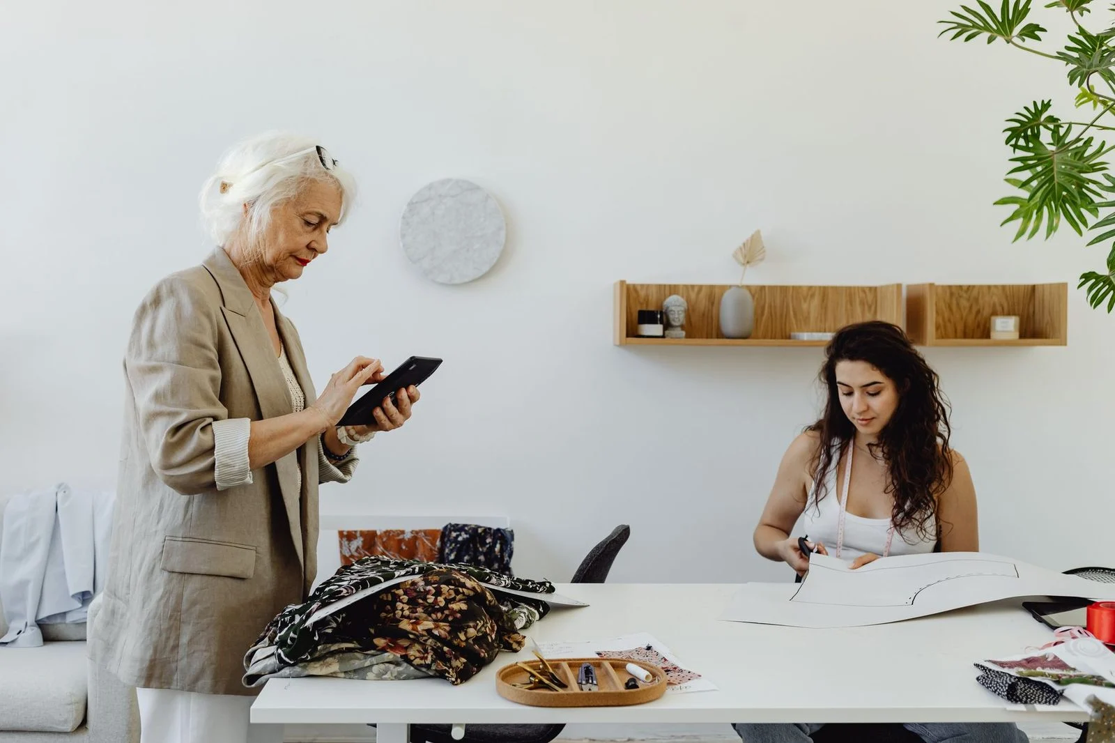 Two women, one elderly and one young, sew together indoors.