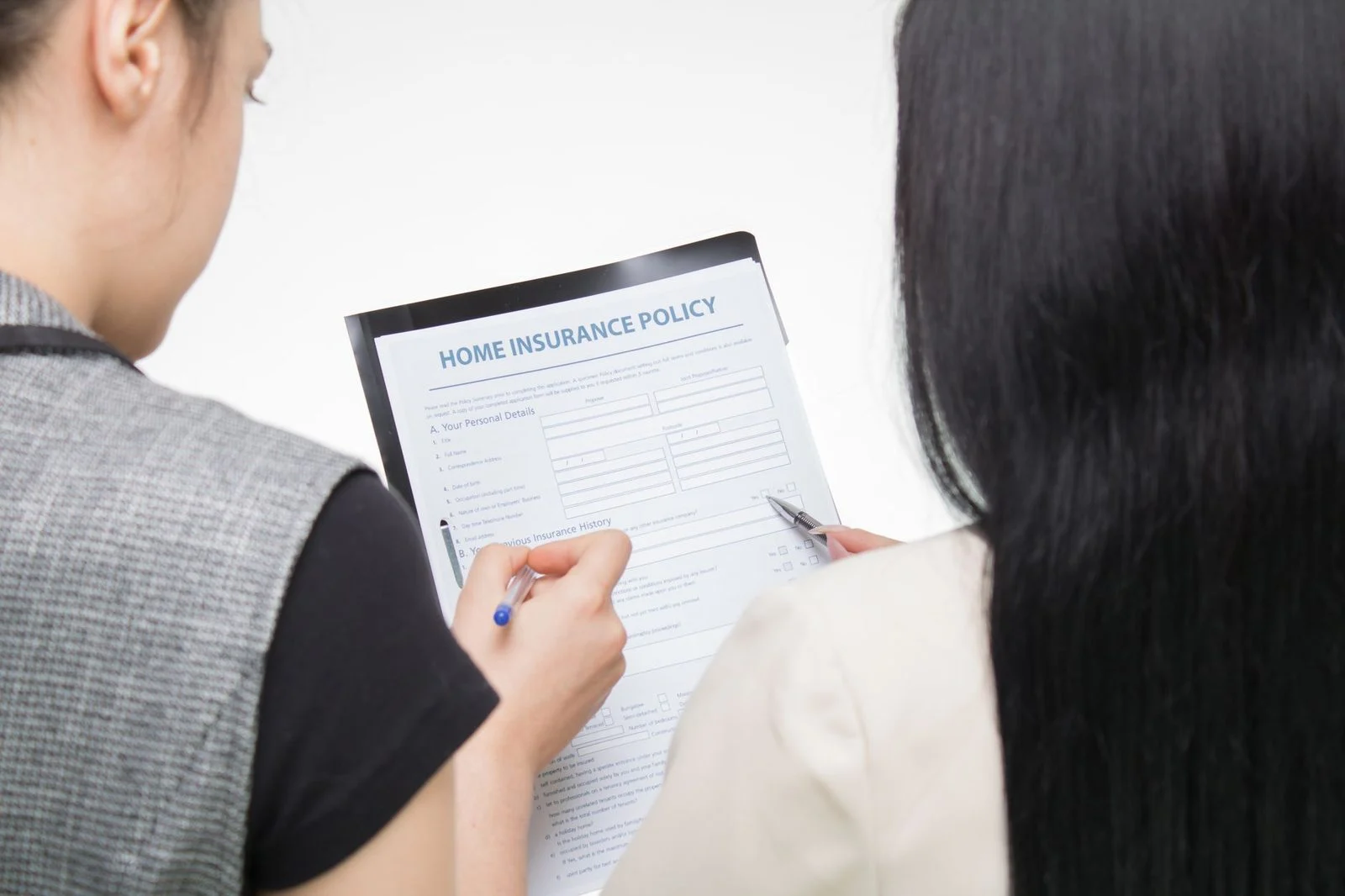 Two women reviewing a home insurance policy form together, focused on the details.