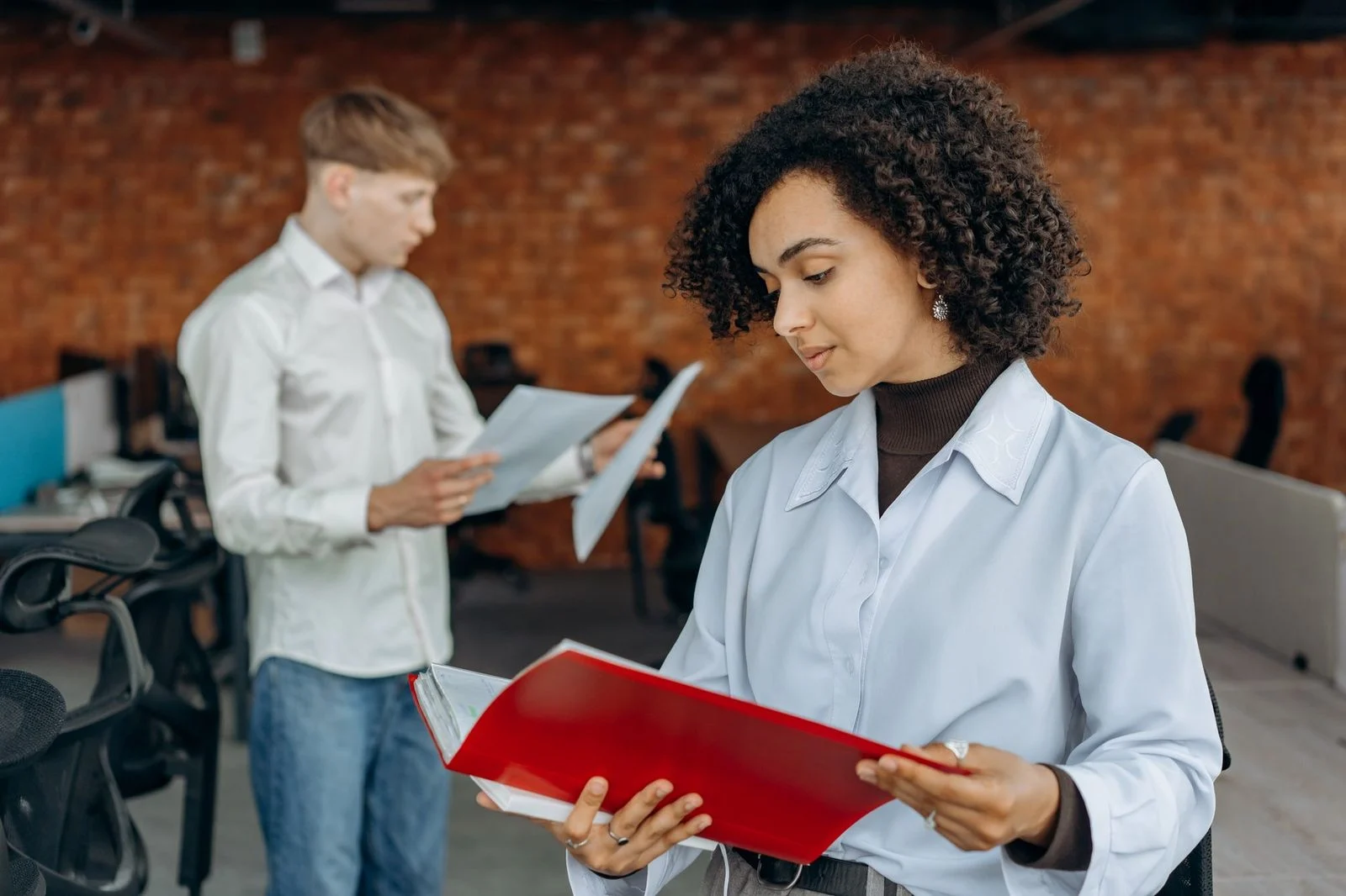 Two young professionals work together on finance reports at a bright, modern office desk.