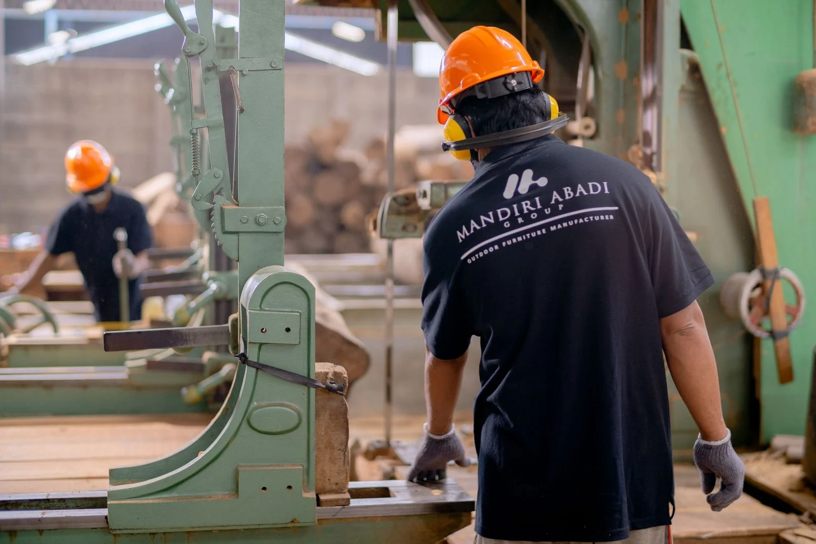 Workers in protective gear operate machinery on a factory floor.