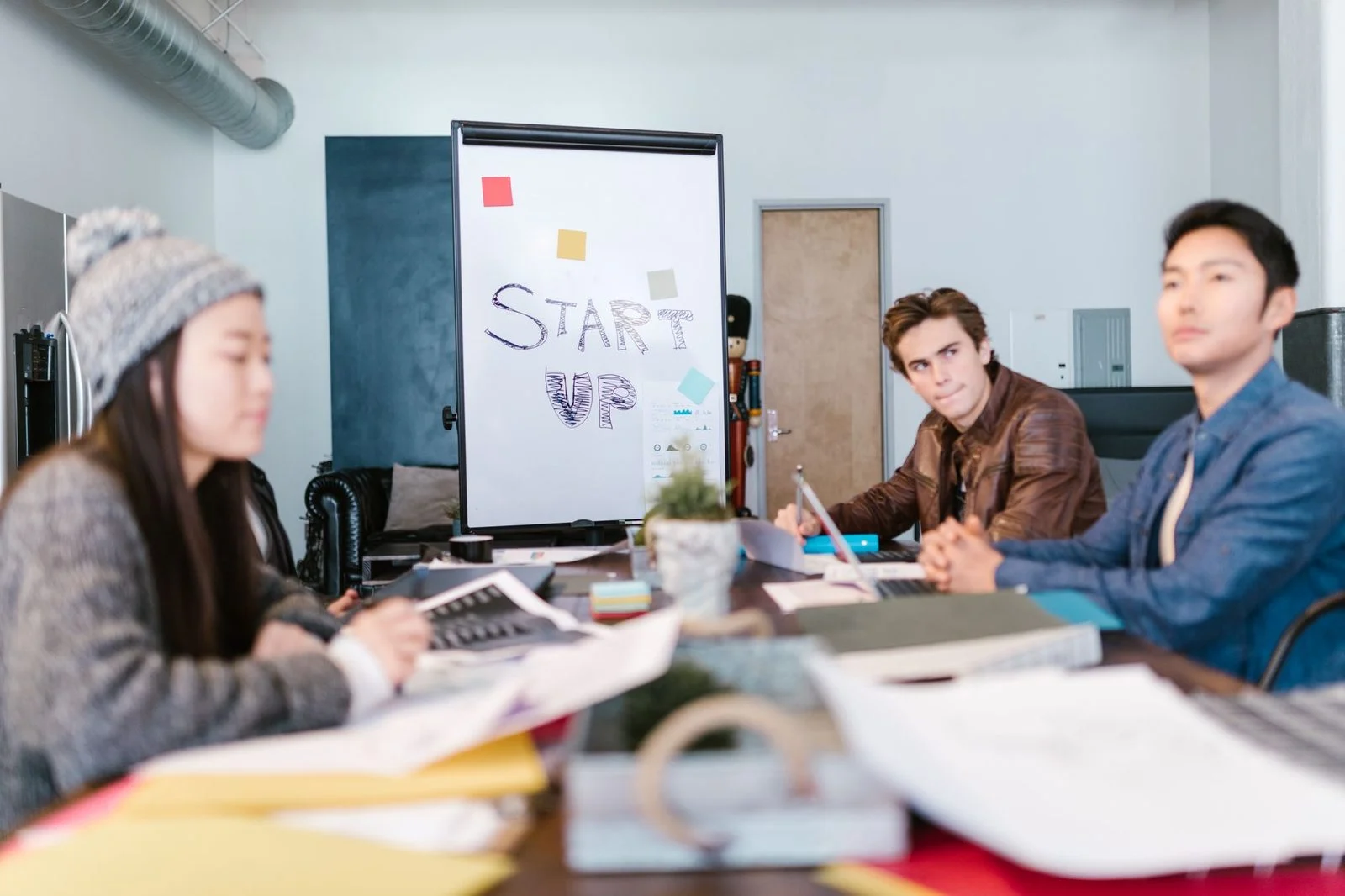 Jóvenes profesionales hacen una lluvia de ideas frente a una pizarra blanca en una oficina luminosa de startup.